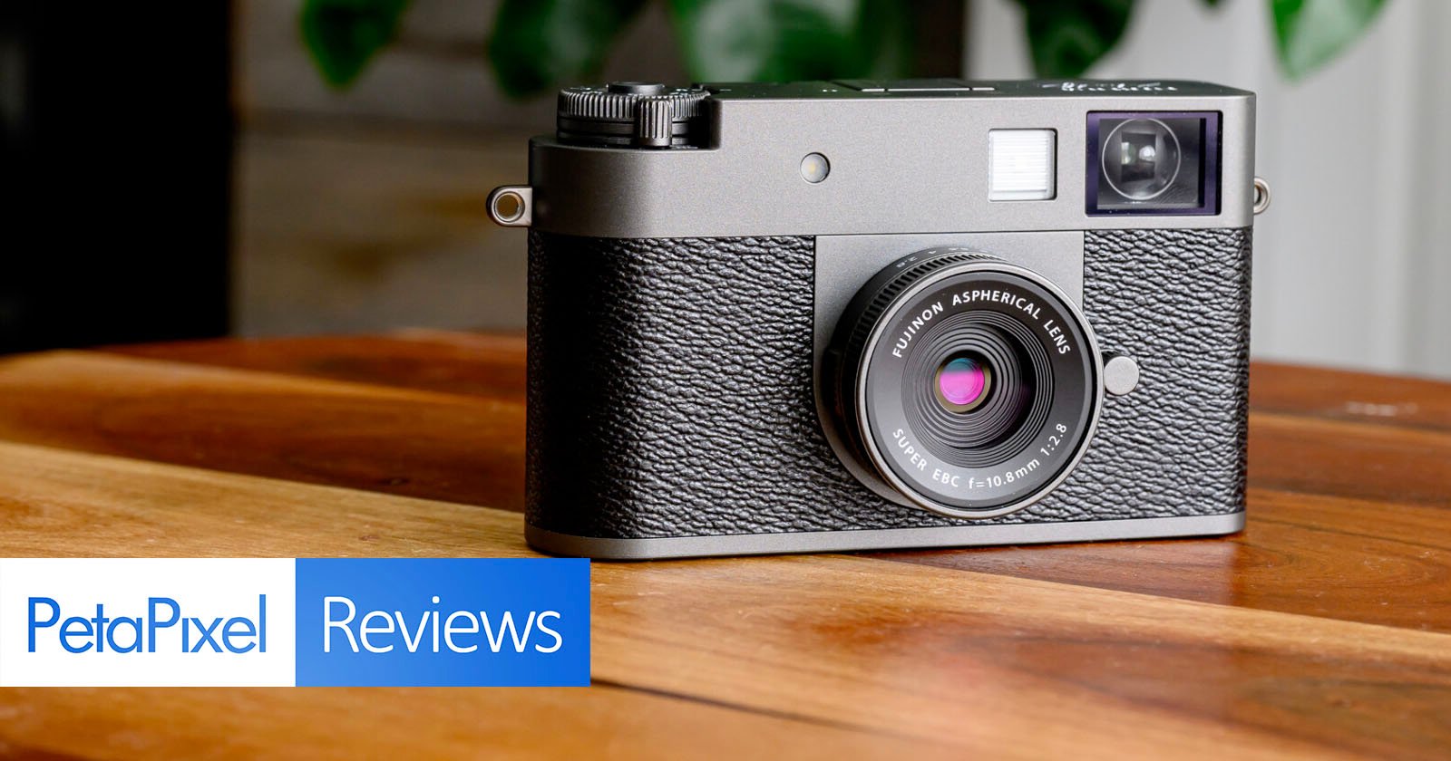 A classic-style digital camera with a textured black body rests on a wooden surface. The lens reads “SUMMICRON ASPHERIC.” In the lower left, the PetaPixel Reviews logo is displayed. A classic-style digital camera with a textured black body rests on a wooden surface. The lens reads “SUMMICRON ASPHERIC.” In the lower left, the PetaPixel Reviews logo is displayed.