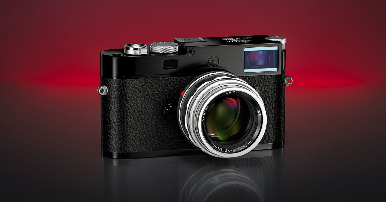 A black Leica camera with a textured grip and silver lens is displayed on a reflective surface against a gradient red and black background. A black Leica camera with a textured grip and silver lens is displayed on a reflective surface against a gradient red and black background.