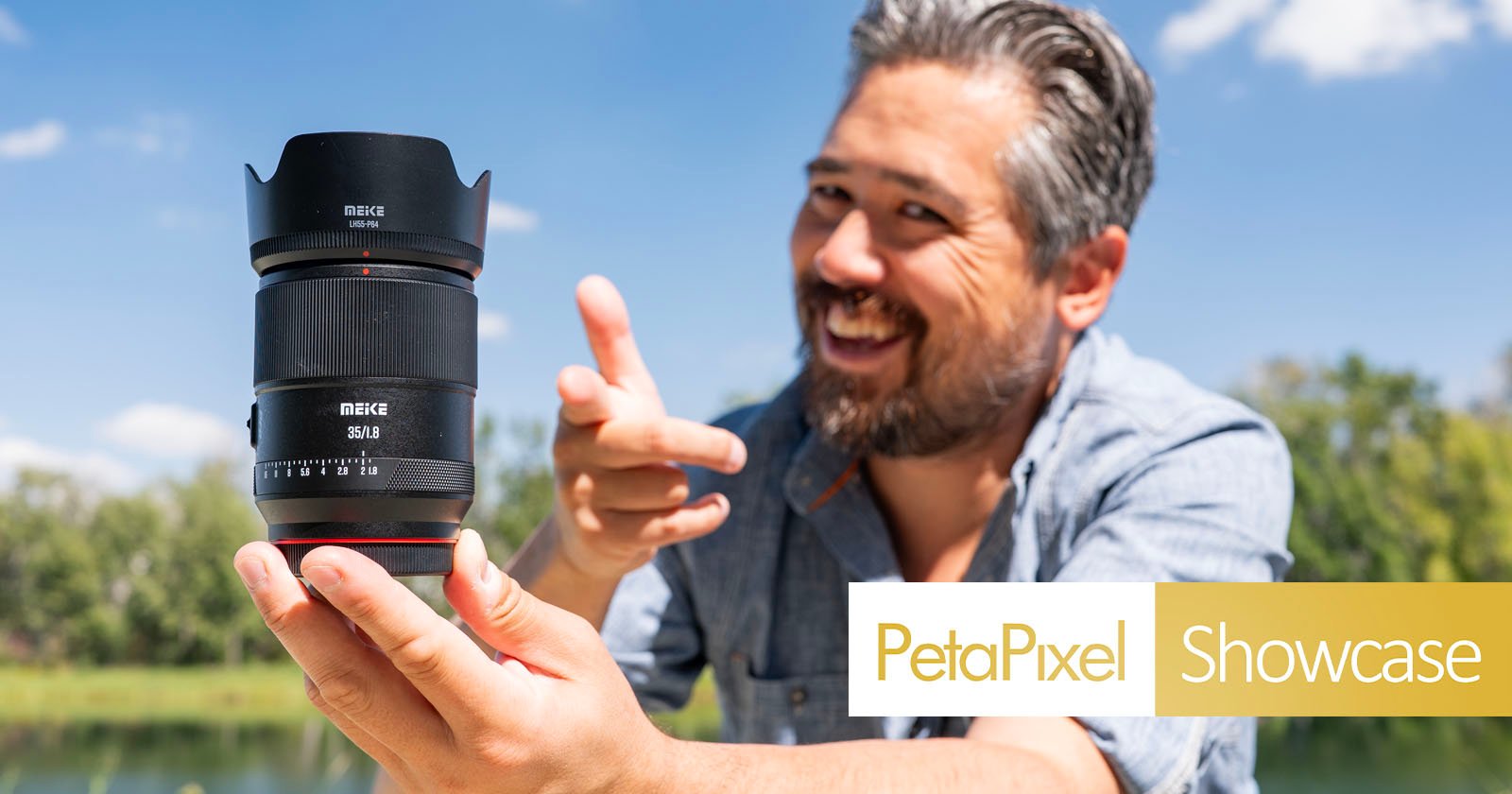 A smiling man outdoors holds up a large camera lens with his left hand and gestures toward it with his right. The logo PetaPixel Showcase appears in the lower right corner. Trees and a blue sky are in the background. A smiling man outdoors holds up a large camera lens with his left hand and gestures toward it with his right. The logo PetaPixel Showcase appears in the lower right corner. Trees and a blue sky are in the background.