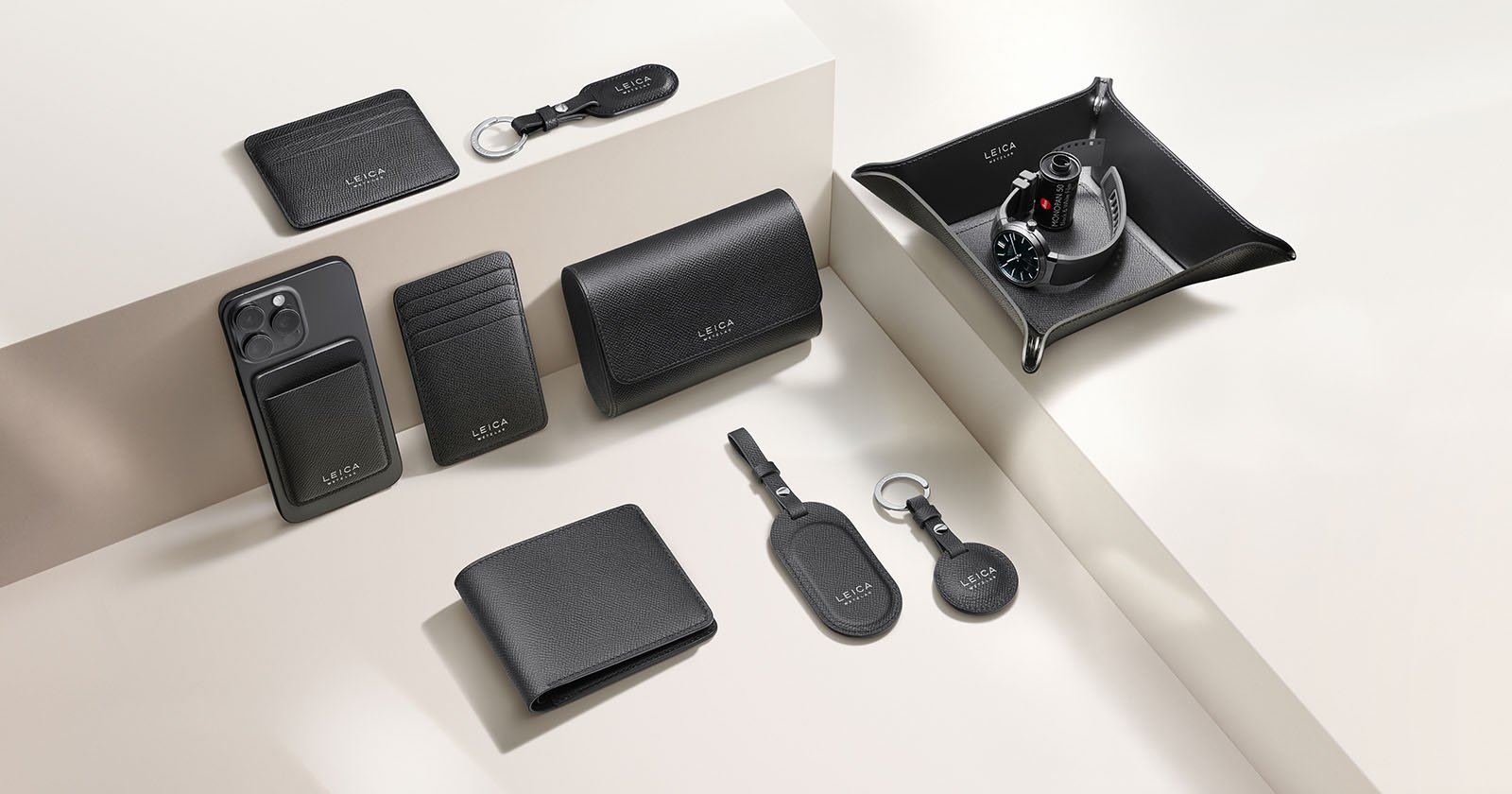 A variety of black leather accessories, including wallets, card holders, keychains, and a valet tray, are neatly arranged on a light beige surface and steps. Some items are embossed with “LUCRIN GENEVA” in white. A variety of black leather accessories, including wallets, card holders, keychains, and a valet tray, are neatly arranged on a light beige surface and steps. Some items are embossed with “LUCRIN GENEVA” in white.