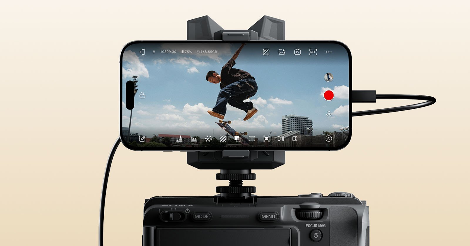 A smartphone mounted on a camera records a skateboarder mid-jump against a blue sky with clouds and distant buildings, with camera interface icons visible on the phone's screen. A smartphone mounted on a camera records a skateboarder mid-jump against a blue sky with clouds and distant buildings, with camera interface icons visible on the phone's screen.
