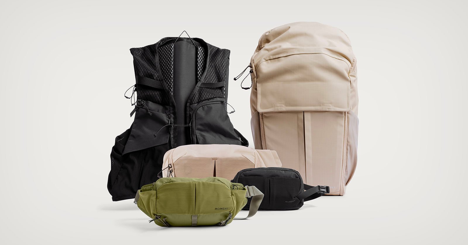 A variety of bags and packs in neutral colors, including a large beige backpack, a black vest-style pack, a green crossbody bag, and two smaller pouches in beige and black, arranged on a plain light background. A variety of bags and packs in neutral colors, including a large beige backpack, a black vest-style pack, a green crossbody bag, and two smaller pouches in beige and black, arranged on a plain light background.